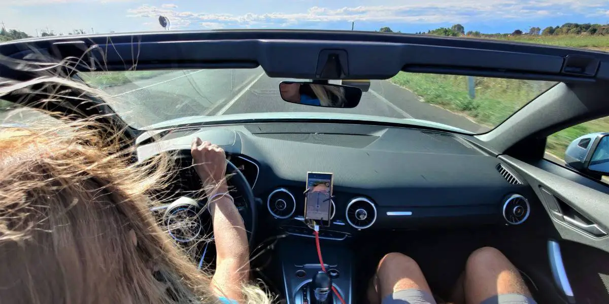 Image of couple driving a convertible with top down
