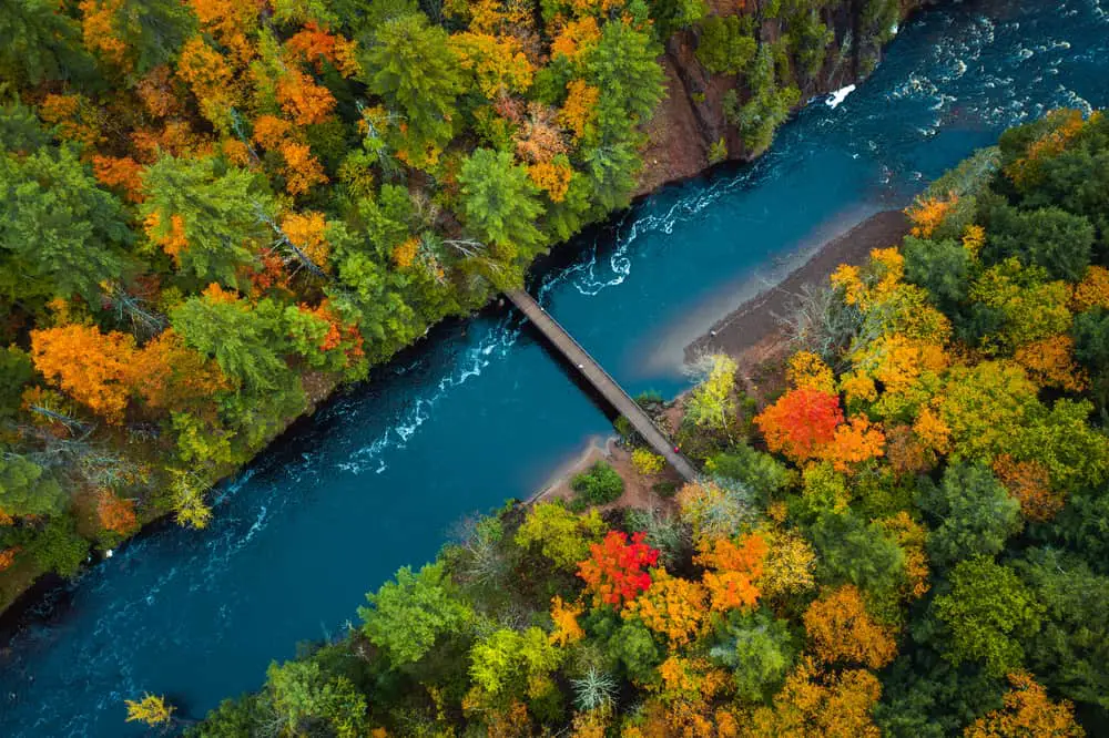 Aerial image of river with bridge connecting two shores. Fall colors are starting the show.