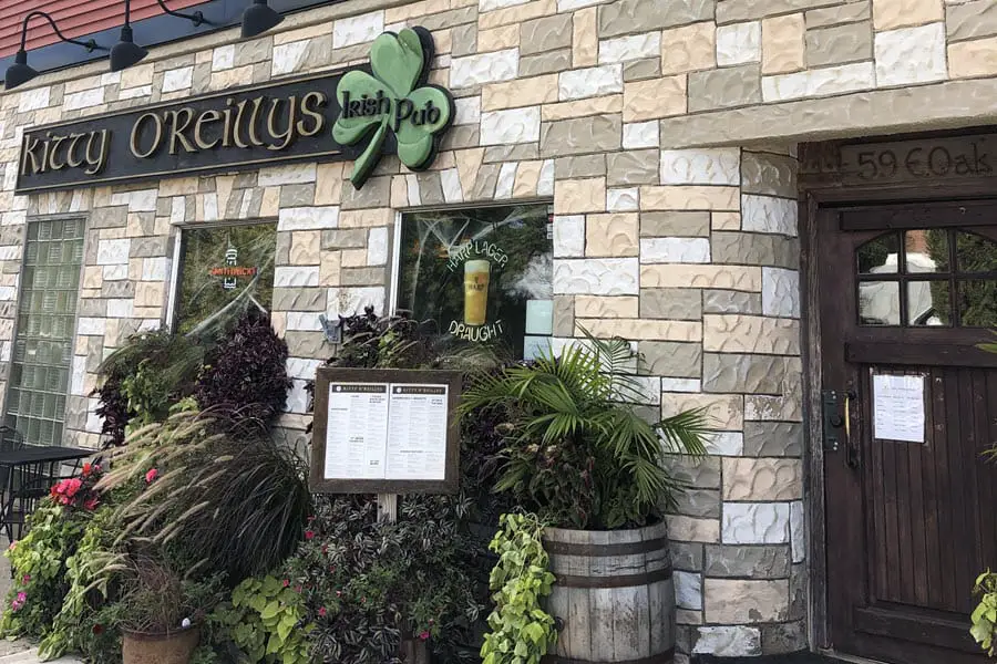 Image of the outside of Kitty O'Reillys Irish Pub. Stone building with a dark wood door. 