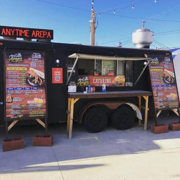 Image of a black food truck with red writing on menus for Anytime Arepa in Milwaukee WI