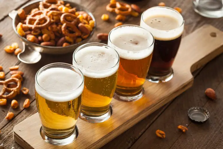 Image of 4 tasting glasses on wooden serving plank full of beer