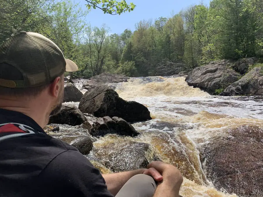 Image of Craig sitting on a rock viewing Red Granite Falls in Copper Falls State Park Wisconsin