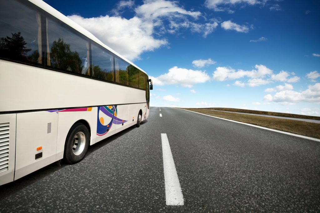 Image of open road with a bus on the left driving down the road