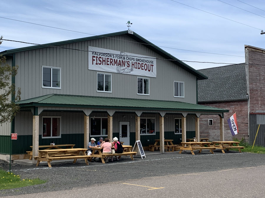 Image of the outside of Halverson's Fish shop. Picnic tables out front with people enjoying lunch