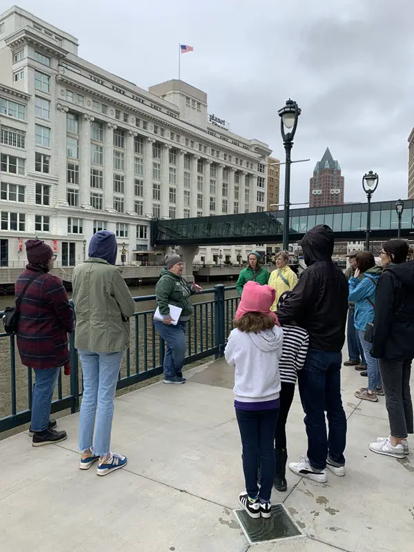 Image of Historic Milwaukee Walking tour. Group of people standing along the milwaukee river with tour guide