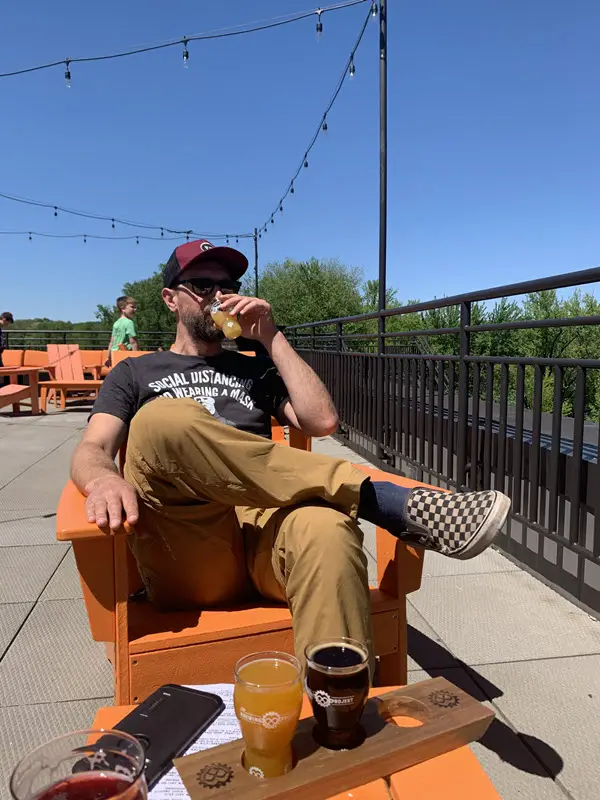 Craig sitting on chair on patio sampling a beer from Brewing Projekt in Eau Claire WI