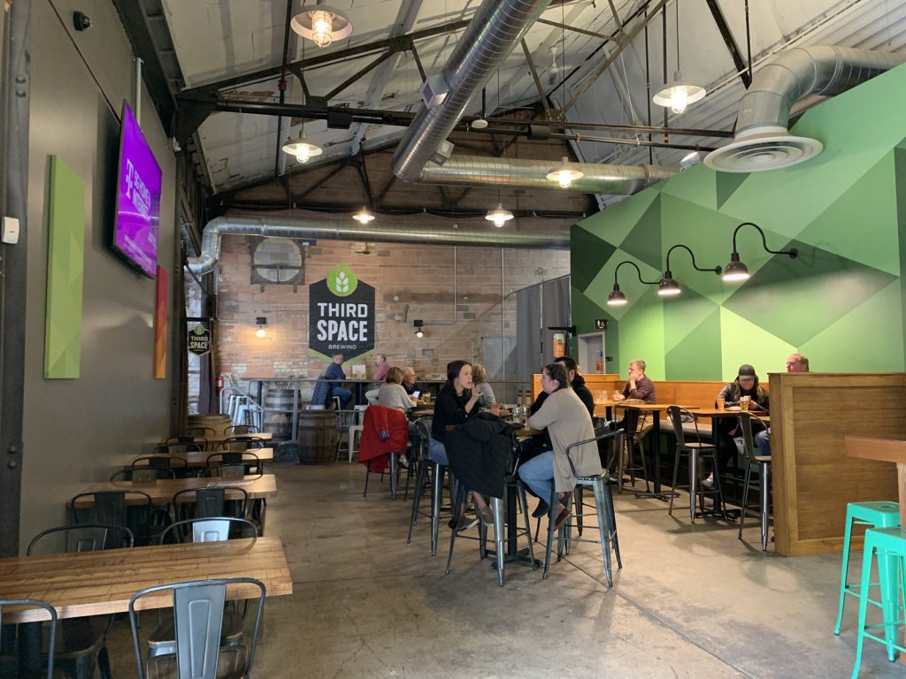 Image of people drinking at tables inside of Third Space Brewing in Milwaukee Wisconsin